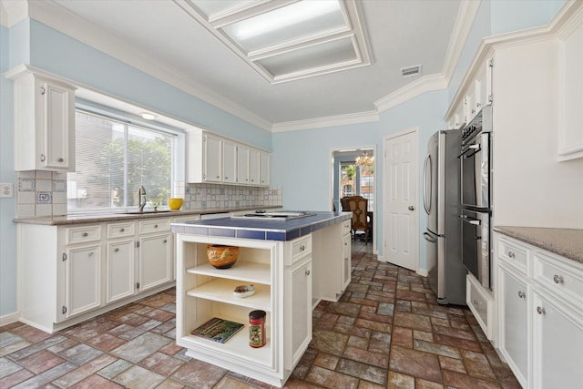 kitchen featuring a center island, a sink, stainless steel appliances, white cabinetry, and a wealth of natural light