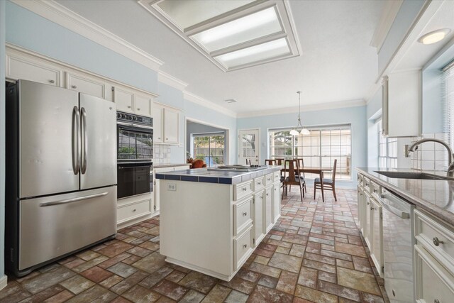 kitchen with a center island, backsplash, sink, appliances with stainless steel finishes, and decorative light fixtures