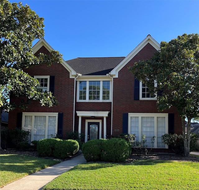 view of front of house featuring brick siding and a front lawn