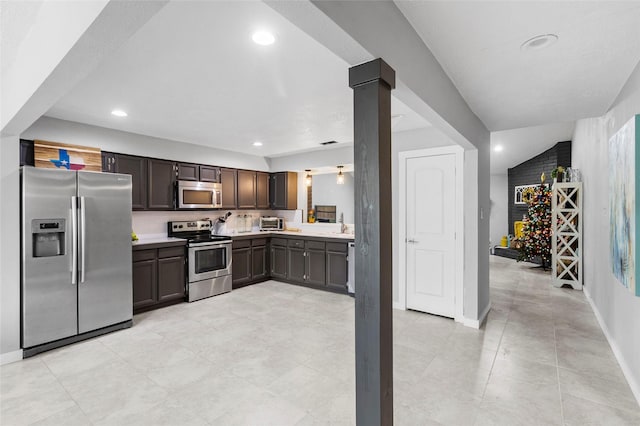 kitchen with ornate columns, dark brown cabinets, light tile patterned flooring, and appliances with stainless steel finishes