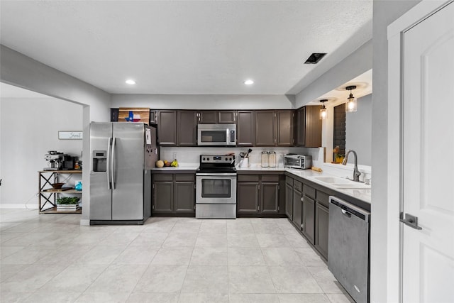 kitchen with dark brown cabinetry, sink, light tile patterned floors, and stainless steel appliances