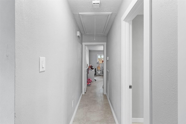 hallway featuring light tile patterned floors and a textured ceiling