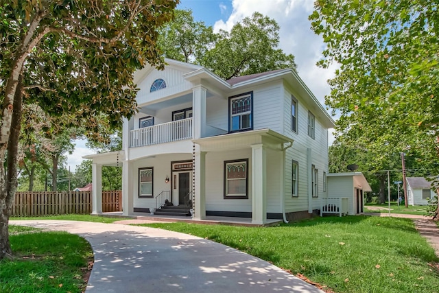 greek revival inspired property with covered porch, a balcony, and a front yard