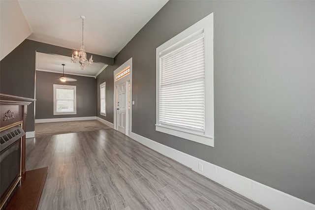 foyer with heating unit, ornamental molding, wood-type flooring, and a notable chandelier