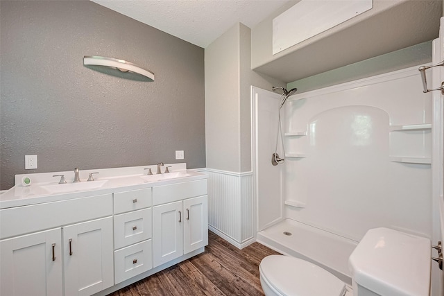 bathroom featuring walk in shower, vanity, a textured ceiling, hardwood / wood-style floors, and toilet