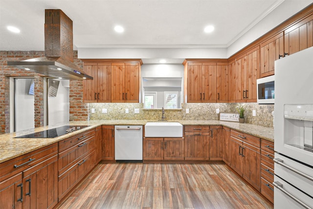 kitchen featuring sink, island exhaust hood, wood-type flooring, white appliances, and ornamental molding