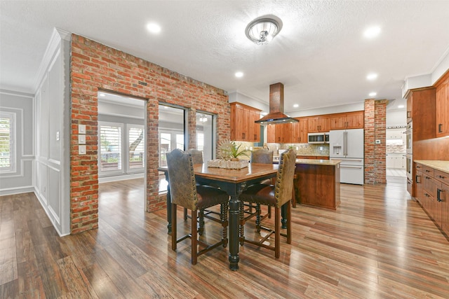 dining room with crown molding, a healthy amount of sunlight, a textured ceiling, and hardwood / wood-style flooring