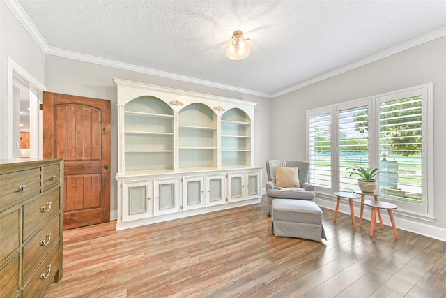 living area with ornamental molding, a textured ceiling, and light hardwood / wood-style flooring