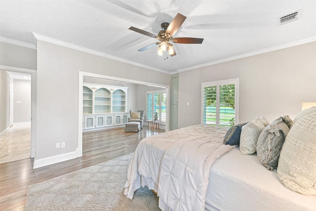 bedroom with ceiling fan, crown molding, wood-type flooring, and a textured ceiling