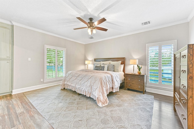 bedroom featuring light hardwood / wood-style floors, multiple windows, crown molding, and ceiling fan