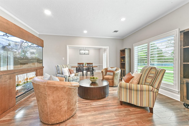 living room with crown molding, wood-type flooring, and a textured ceiling