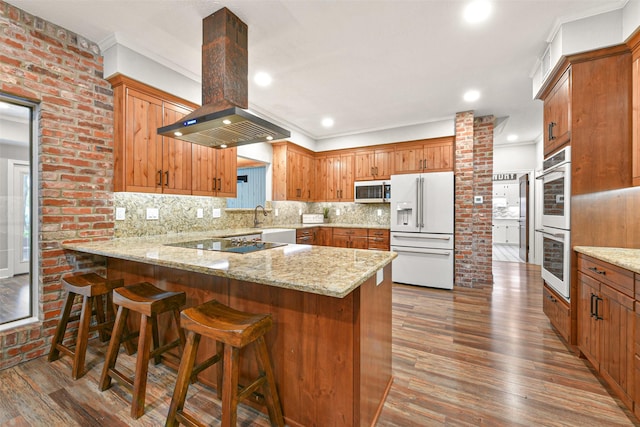 kitchen with hardwood / wood-style floors, kitchen peninsula, white fridge with ice dispenser, and island exhaust hood