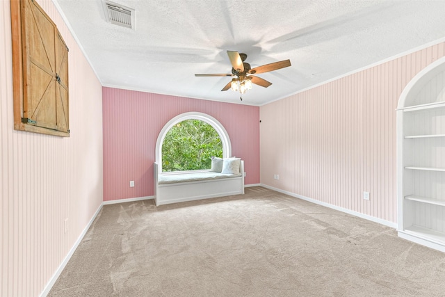 empty room with light carpet, crown molding, ceiling fan, and a textured ceiling