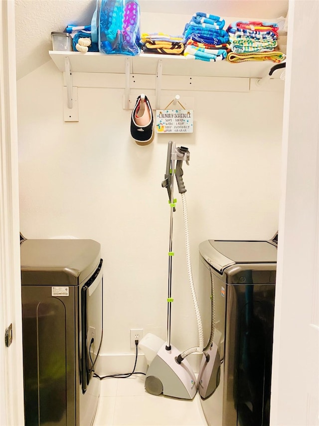 clothes washing area with washer and dryer, light tile patterned floors, and a textured ceiling