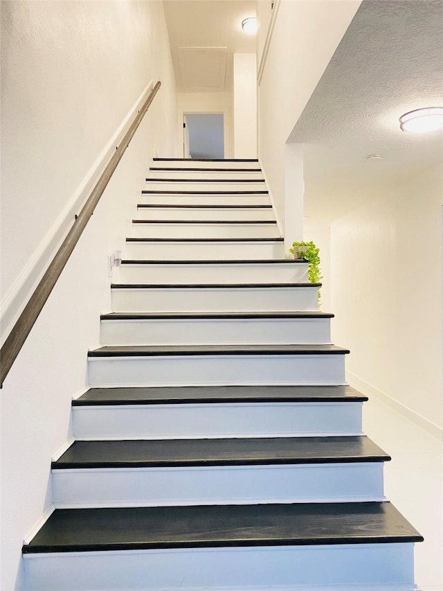 staircase with a textured ceiling