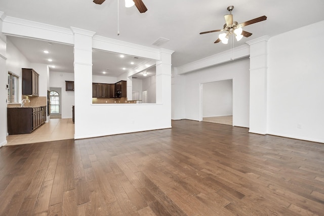 unfurnished living room featuring hardwood / wood-style flooring, ceiling fan, ornate columns, and crown molding