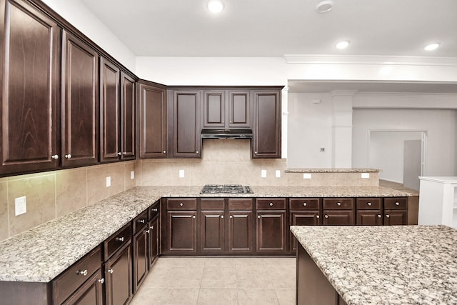 kitchen featuring dark brown cabinets, backsplash, light stone counters, and stainless steel gas stovetop