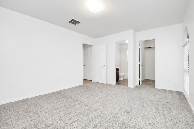 unfurnished bedroom featuring light colored carpet and connected bathroom