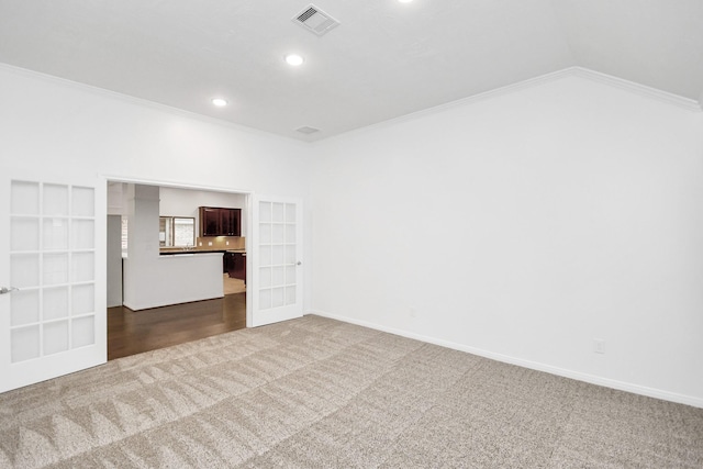 spare room featuring carpet, french doors, vaulted ceiling, and ornamental molding