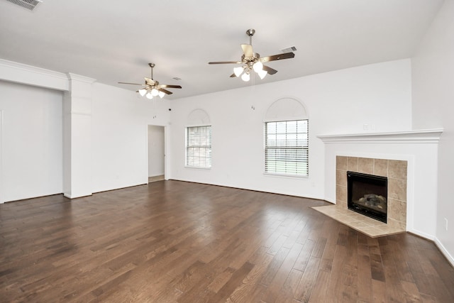 unfurnished living room with a tiled fireplace, ceiling fan, and dark hardwood / wood-style flooring