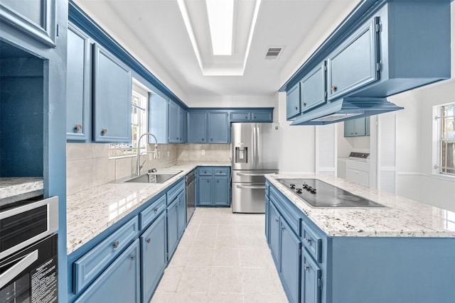 kitchen with independent washer and dryer, a wealth of natural light, sink, and appliances with stainless steel finishes