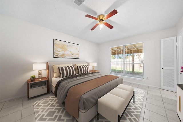 bedroom featuring ceiling fan, light tile patterned flooring, and a textured ceiling