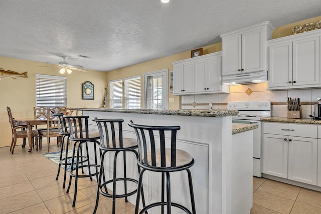 818 Sea Shell Dr, Freeport, TX 77541 - kitchen featuring ceiling fan, light tile patterned floors, white cabinets, white electric range, and a kitchen island