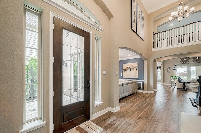 entrance foyer with a chandelier, a towering ceiling, hardwood / wood-style flooring, and ornamental molding