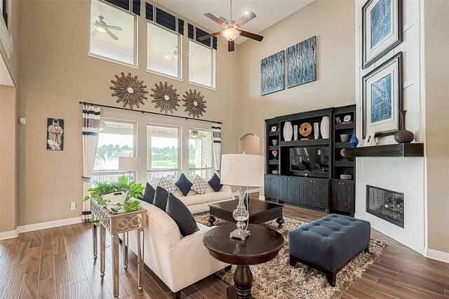 living room with wood-type flooring, a towering ceiling, and ceiling fan