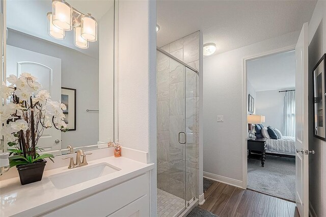 bathroom featuring vanity, hardwood / wood-style flooring, an inviting chandelier, and a shower with door