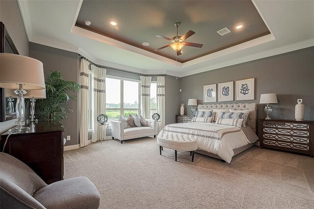 carpeted bedroom with a tray ceiling, ceiling fan, and ornamental molding