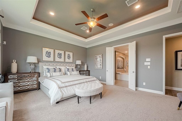 carpeted bedroom with a tray ceiling, connected bathroom, ceiling fan, and ornamental molding