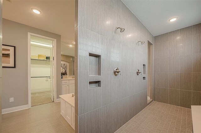 bathroom featuring tile patterned flooring, vanity, and tiled shower