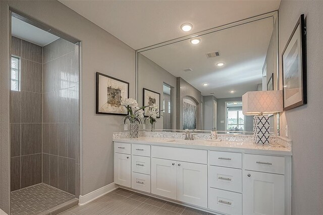 bathroom with a tile shower and vanity