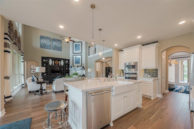 kitchen with a kitchen island with sink, white cabinetry, sink, and stainless steel appliances