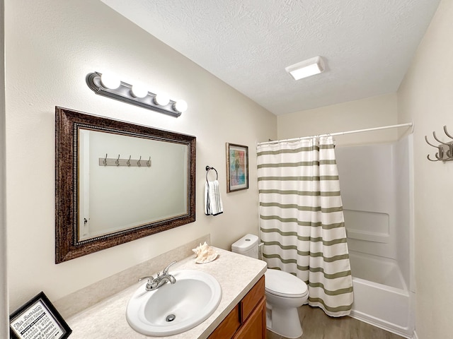 full bathroom with vanity, shower / bath combo, hardwood / wood-style flooring, toilet, and a textured ceiling