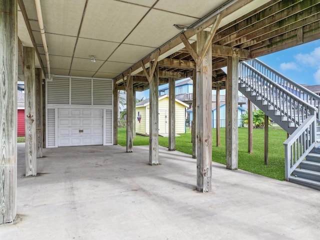 view of patio / terrace featuring a carport, an outdoor structure, and a garage