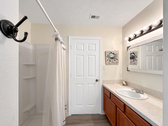 bathroom featuring curtained shower, vanity, a textured ceiling, and hardwood / wood-style flooring