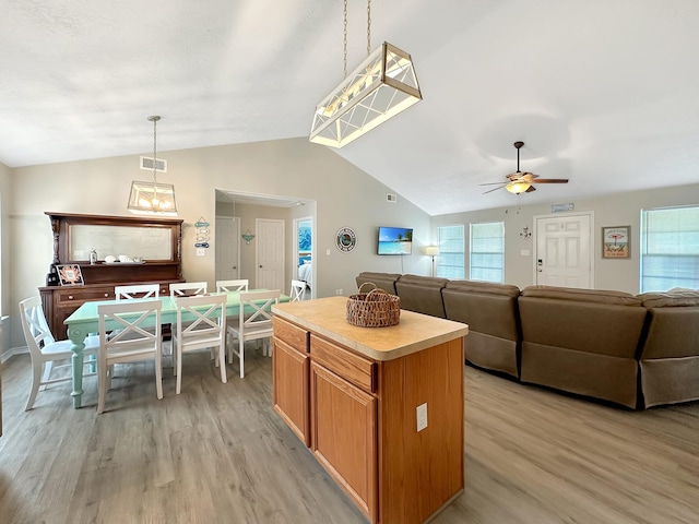 kitchen with a center island, hanging light fixtures, vaulted ceiling, ceiling fan, and light wood-type flooring