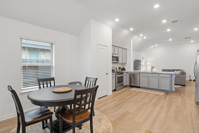 dining area featuring light wood-type flooring and vaulted ceiling