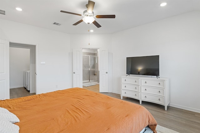 bedroom featuring ensuite bathroom, washer and clothes dryer, ceiling fan, and hardwood / wood-style flooring