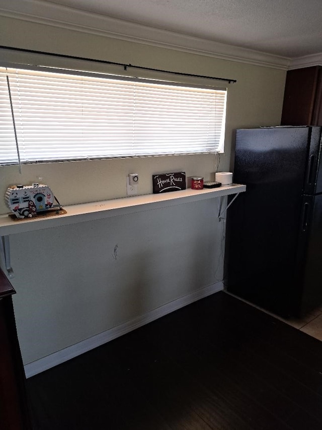 kitchen with black refrigerator, hardwood / wood-style floors, and ornamental molding