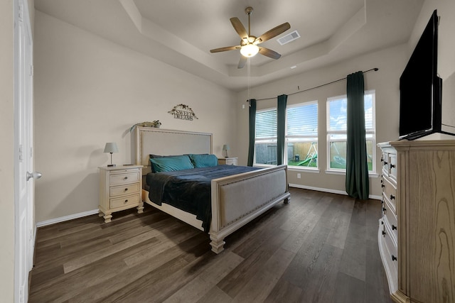 bedroom with a raised ceiling, ceiling fan, and dark hardwood / wood-style flooring