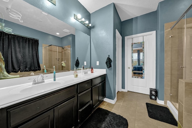 bathroom featuring tile patterned flooring, vanity, tiled shower, and a textured ceiling