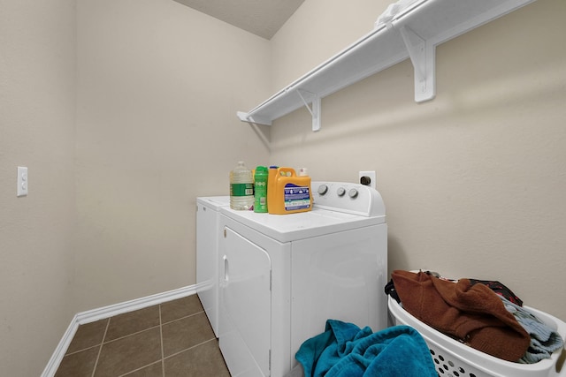 clothes washing area featuring washing machine and dryer and dark tile patterned flooring