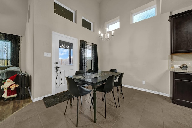 dining area with a notable chandelier, a healthy amount of sunlight, light tile patterned flooring, and a towering ceiling