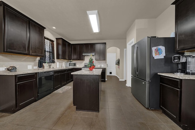 kitchen featuring sink, tasteful backsplash, dark brown cabinets, a kitchen island, and appliances with stainless steel finishes