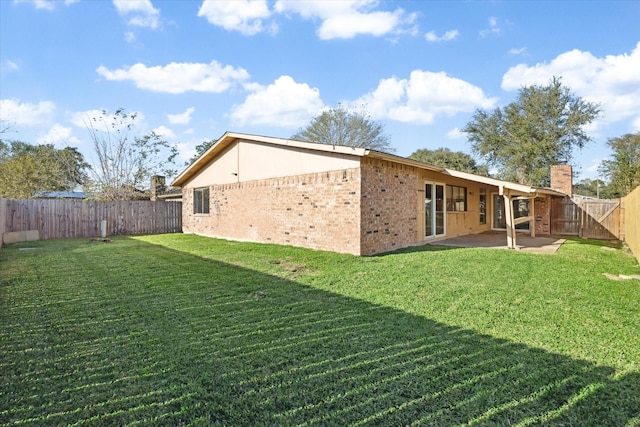 rear view of house featuring a lawn and a patio