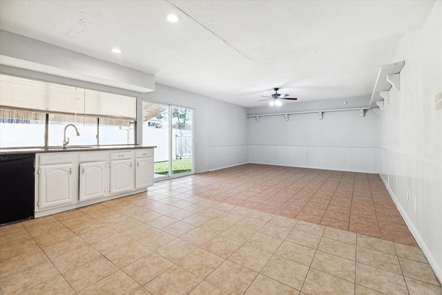 kitchen with white cabinetry, sink, ceiling fan, black dishwasher, and light tile patterned flooring