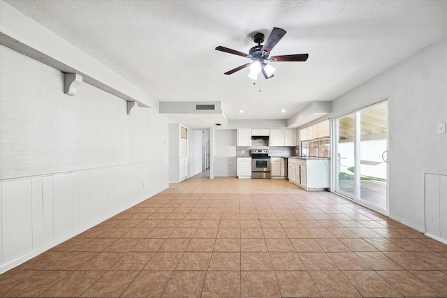 unfurnished living room with a textured ceiling, ceiling fan, beam ceiling, and sink